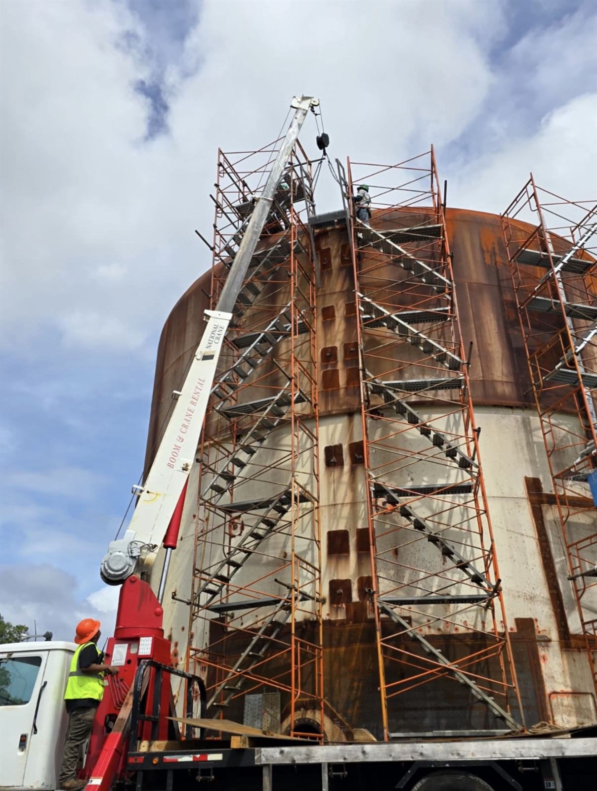 RDE boom truck lifting steel to the top of a scaffolded tank