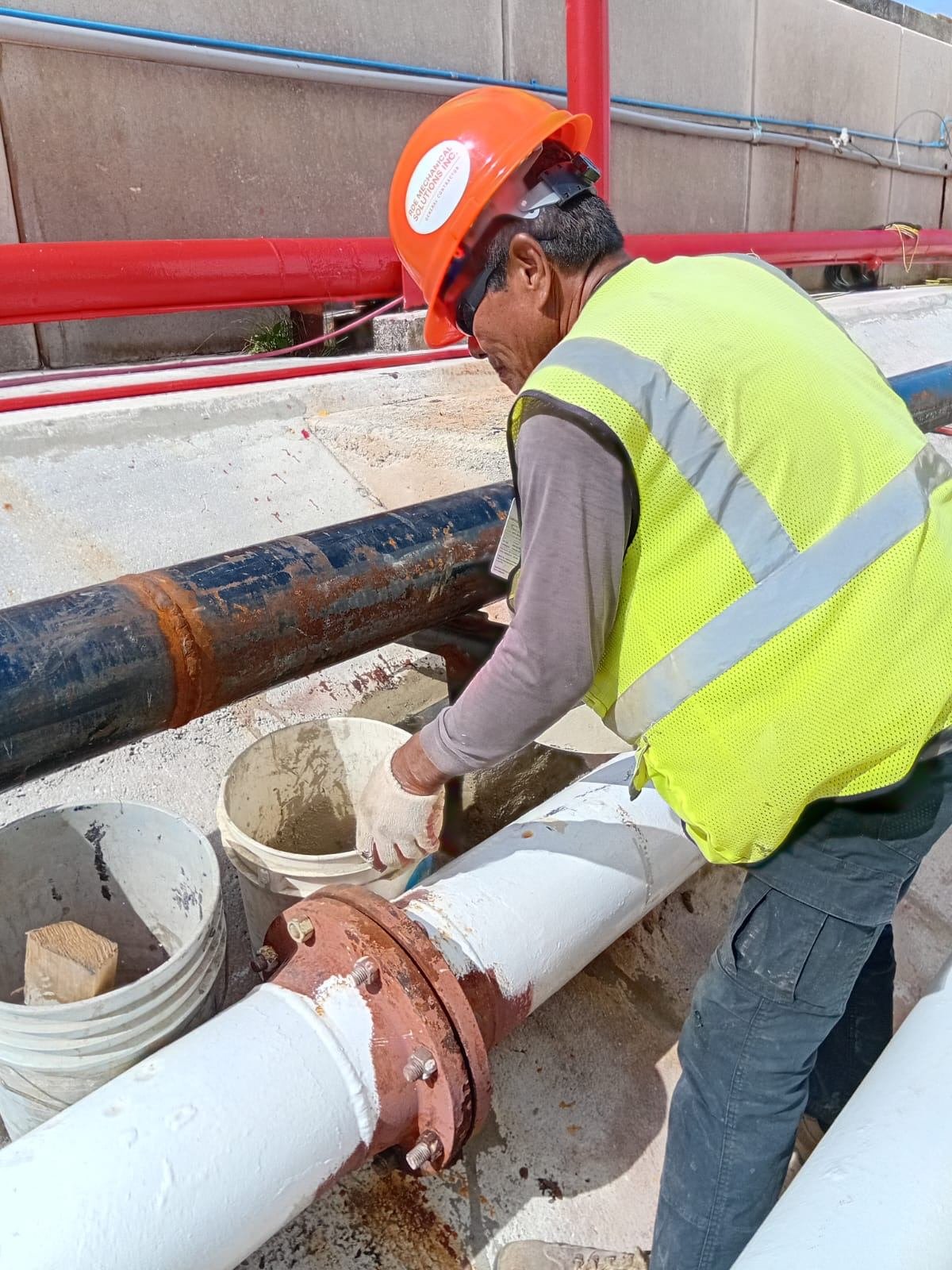 RDE worker in hard hat and safety vest preparing a pipe joint