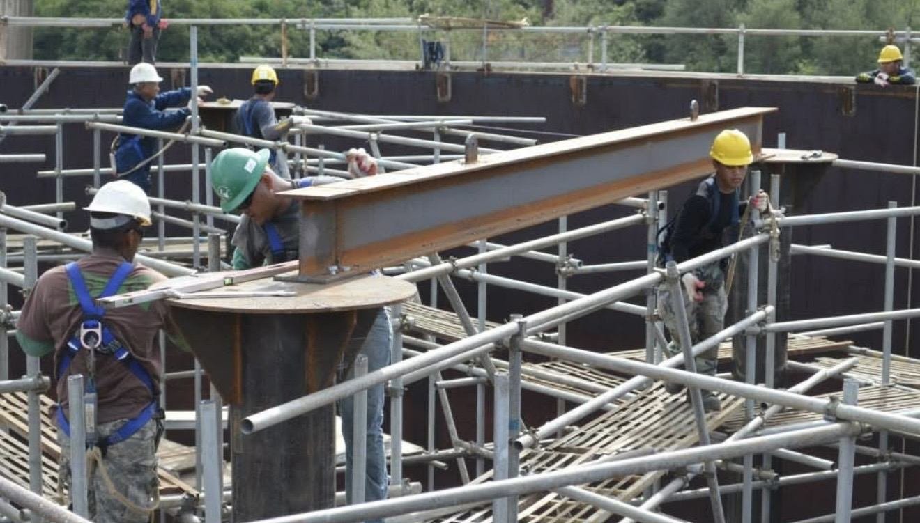 Workers in hard hats erecting steel framing on scaffolding